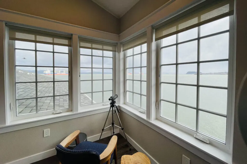 A corner bay window that looks out over the river with a telescope for guests to use in the Wheelhouse on Pier 11.