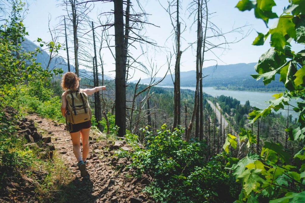 A female hiker points towards Columbia River.