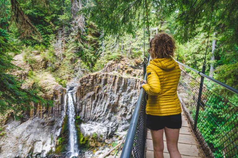 Nina overlooking Drift Creek Falls from a suspension bridge in the forest.