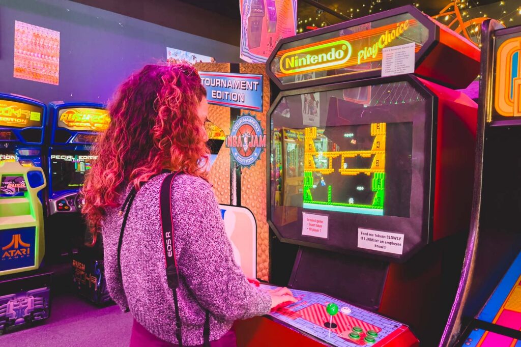 Nina playing a retro arcade game in Gizmos Arcade.