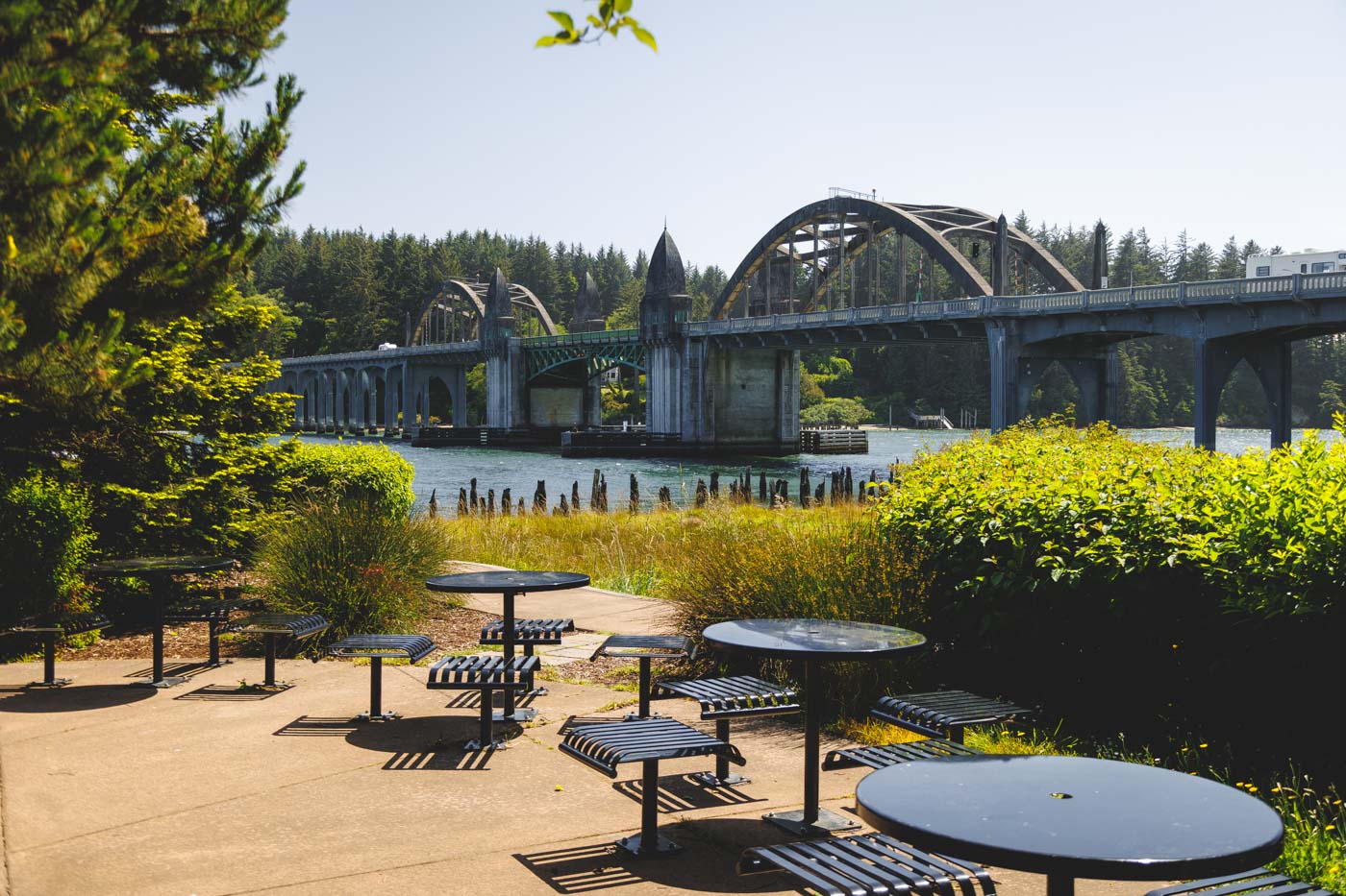 Tables and chairs with a view of a concrete bridge at Siuslaw Interpretive Center in Florence.