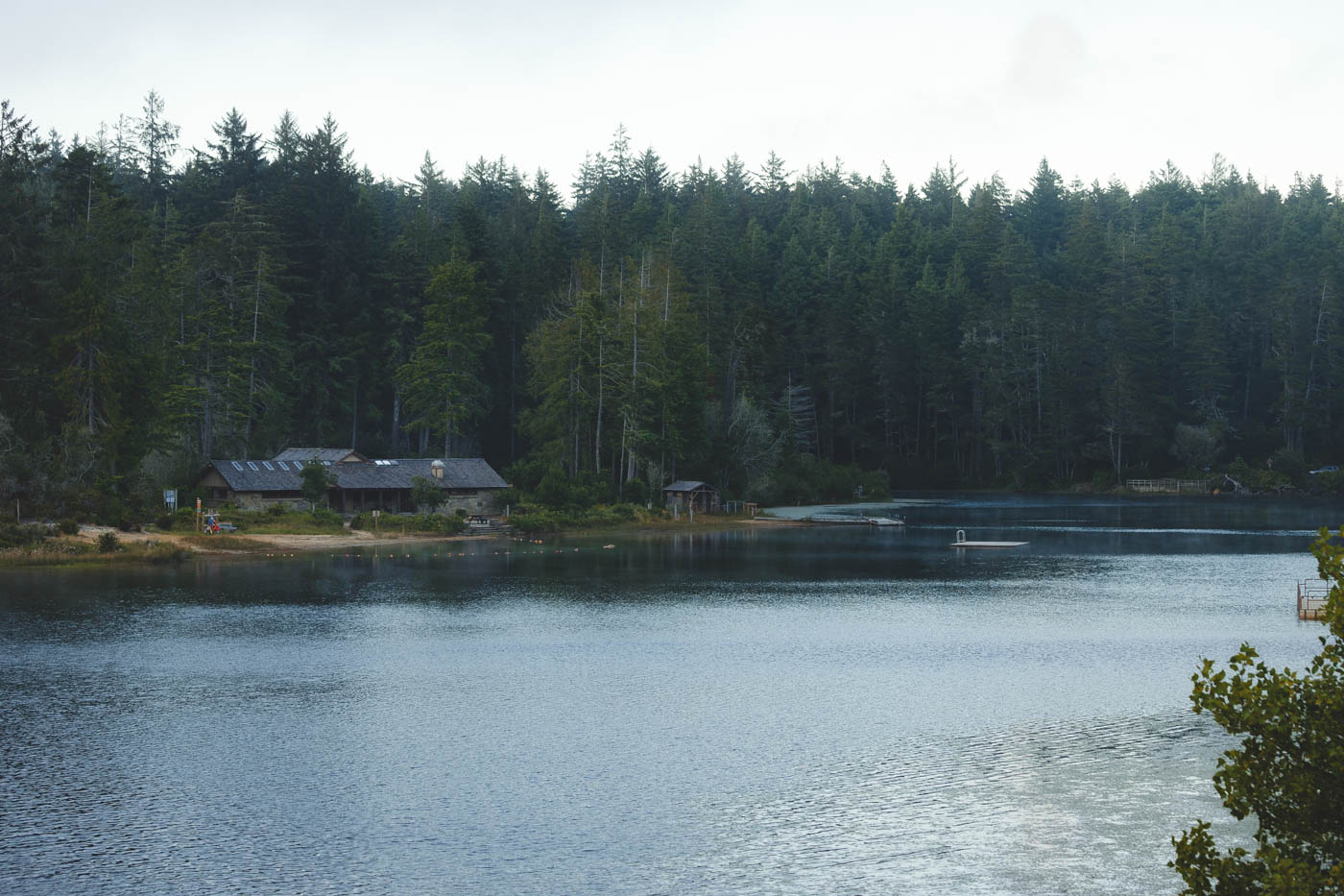 A cabin on the shores of Cleowax Lake with a backdrop of pine trees in Jessie M Honeyman Memorial State Park.