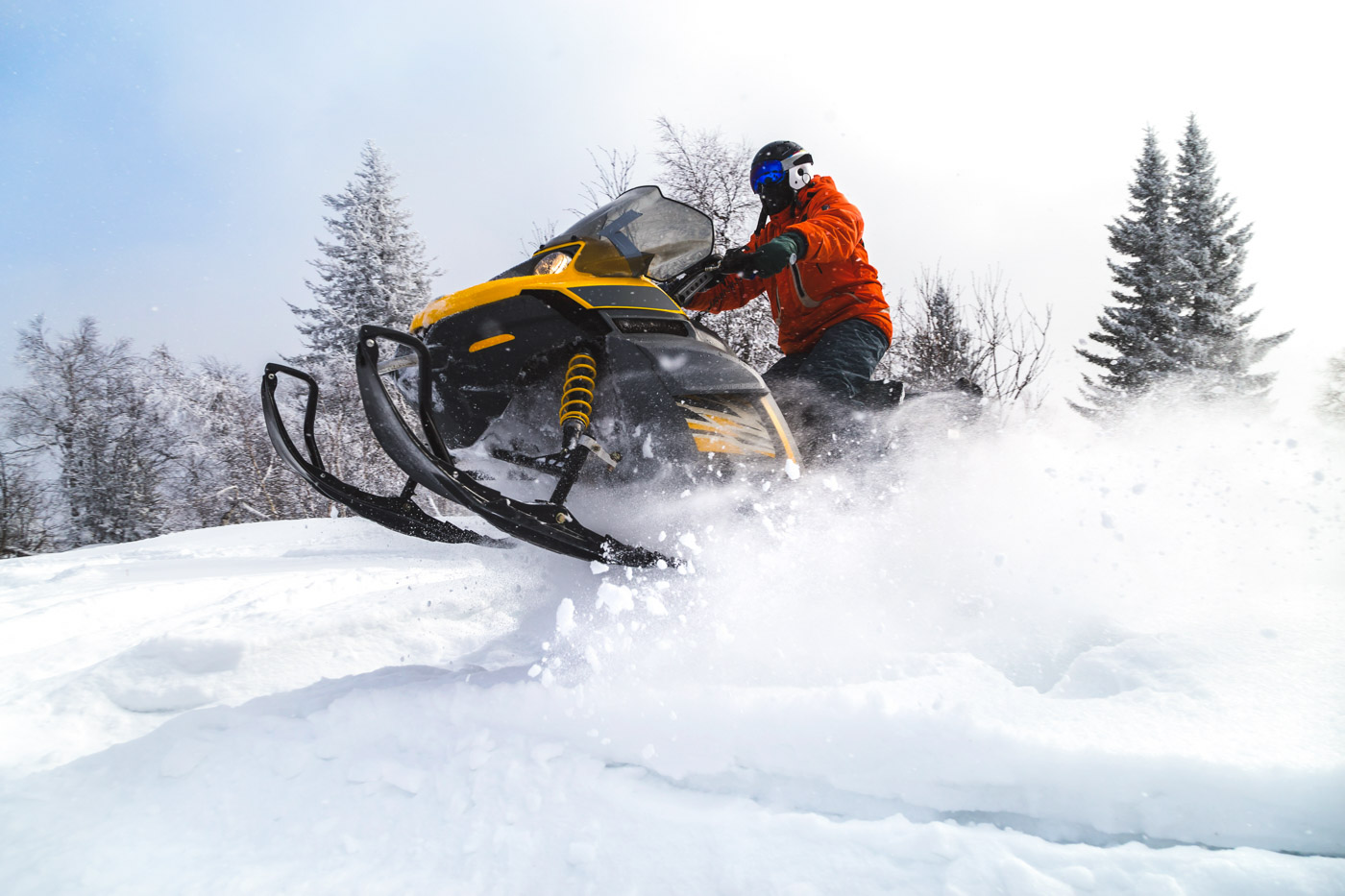 Man ripping a snowmobile through a winter landscape.