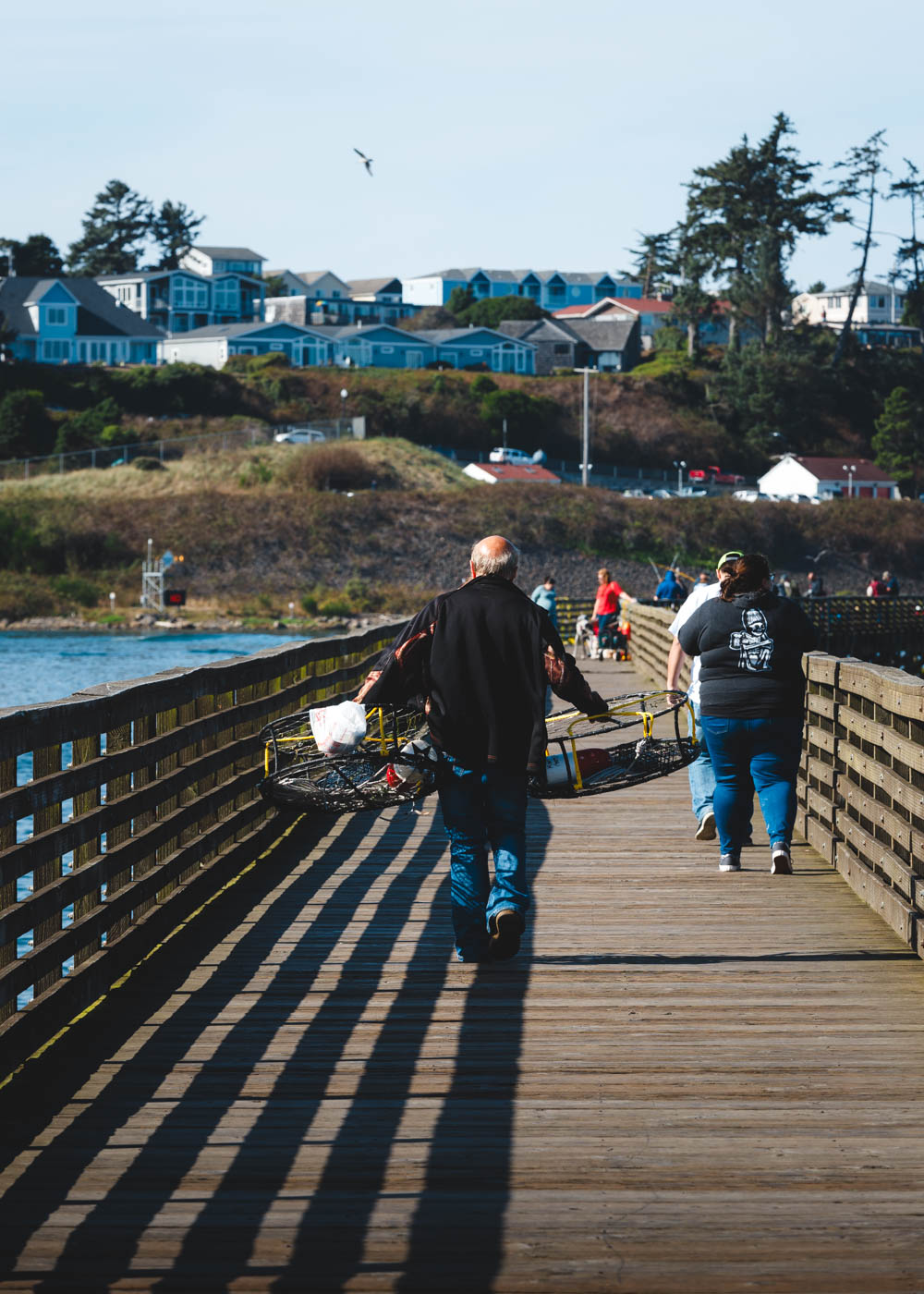 A man holding two crabbing cages walking down a pier in Newport.