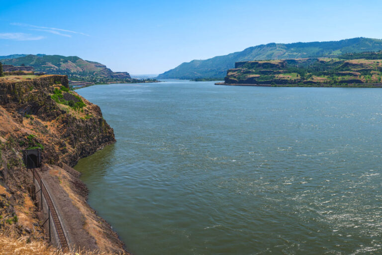 A view of a huge expanse of river and a train track in Columbia River Gorge as seen from the Lyle Cherry Hike on a sunny day.