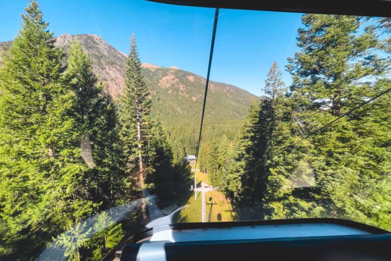 A view looking out from a cable car down a gondola along the Wallowa tramway with views of forests.