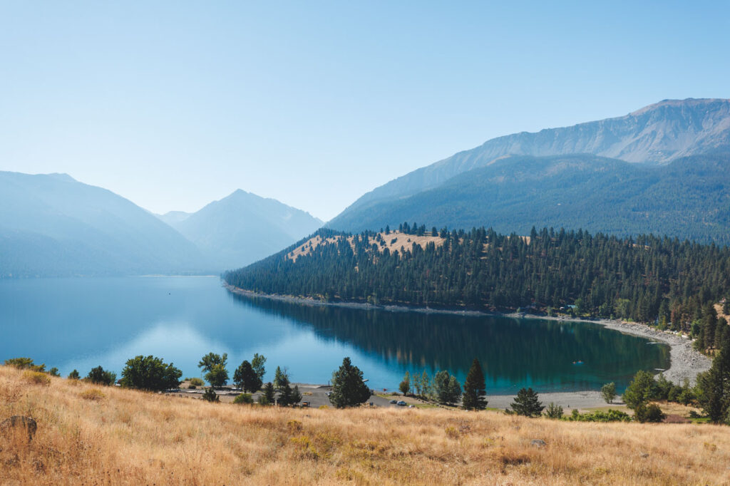 A view over a large portion of Wallowa Lake and over to mountains and forests on a sunny day.