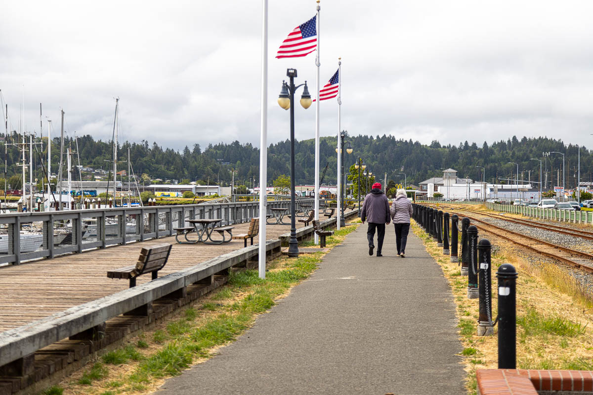 Two people walking on Coos Bay with American flags waving.