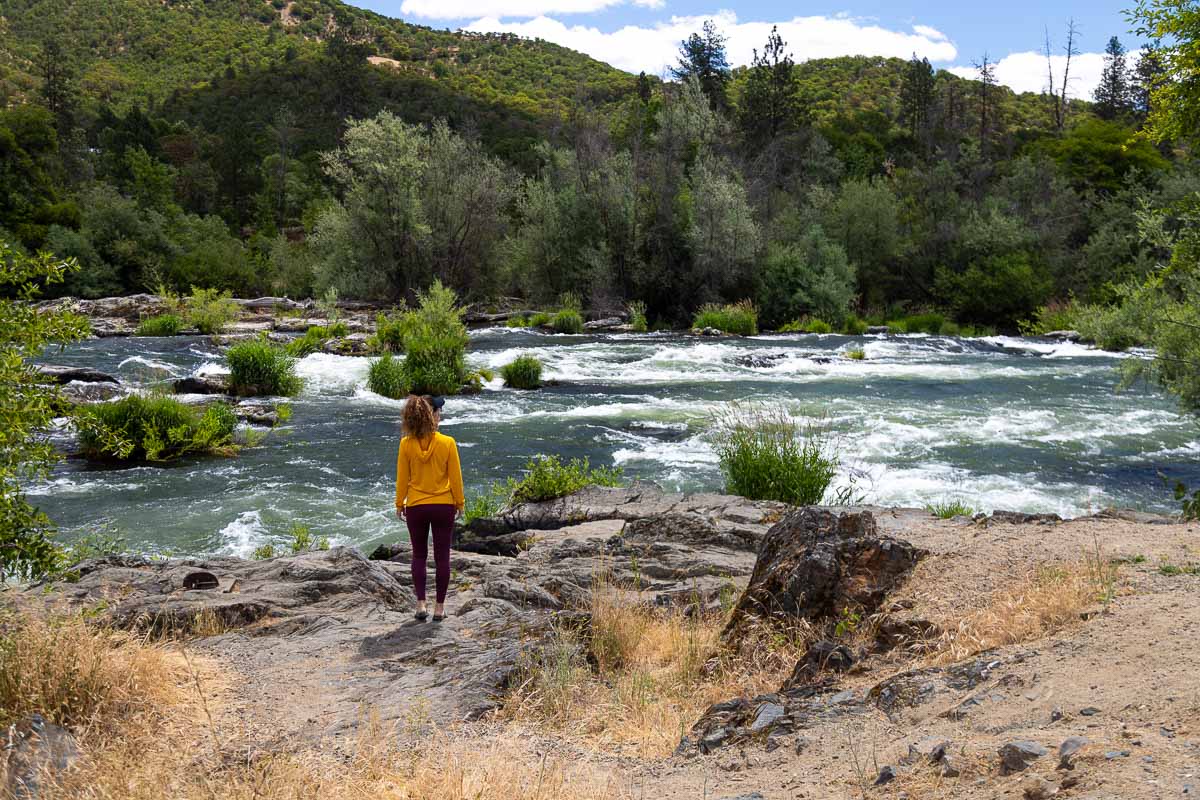 Ti'lomikh Falls & Gold Hill Trail Nina standing at river view.