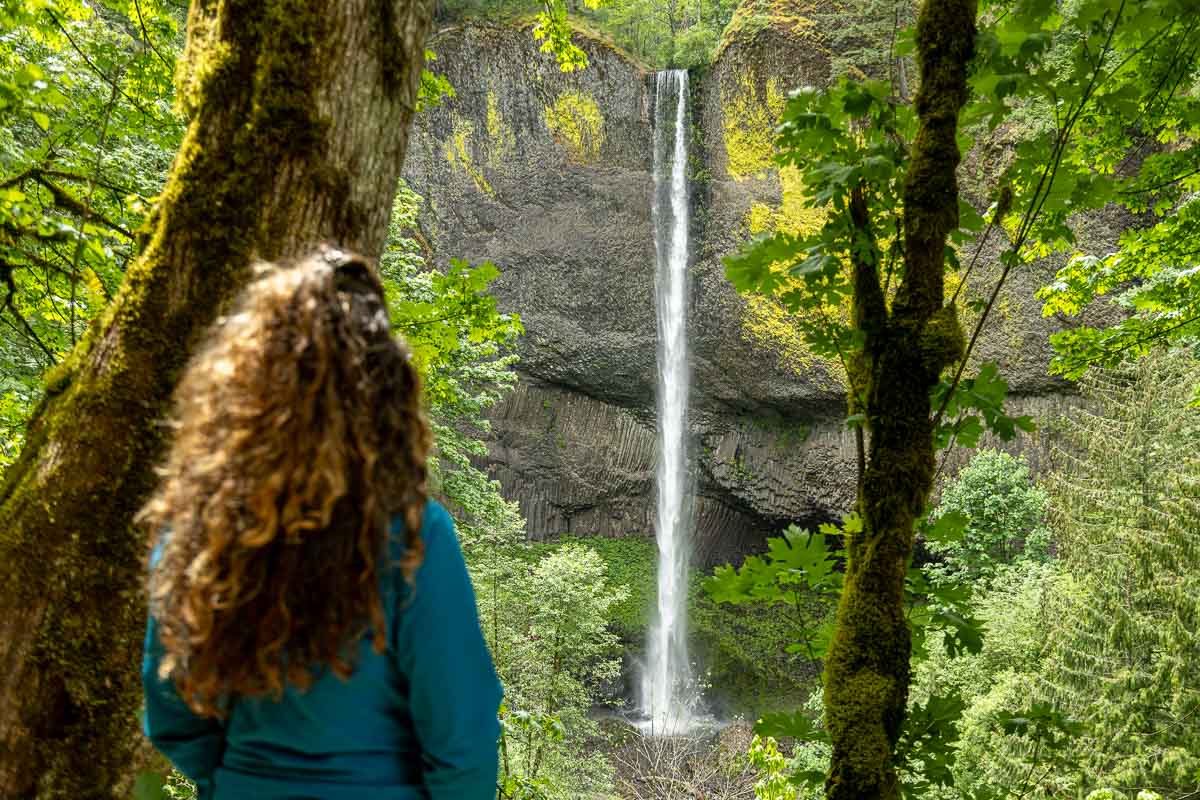 Nina standing outof focus with Latourell Falls behind.