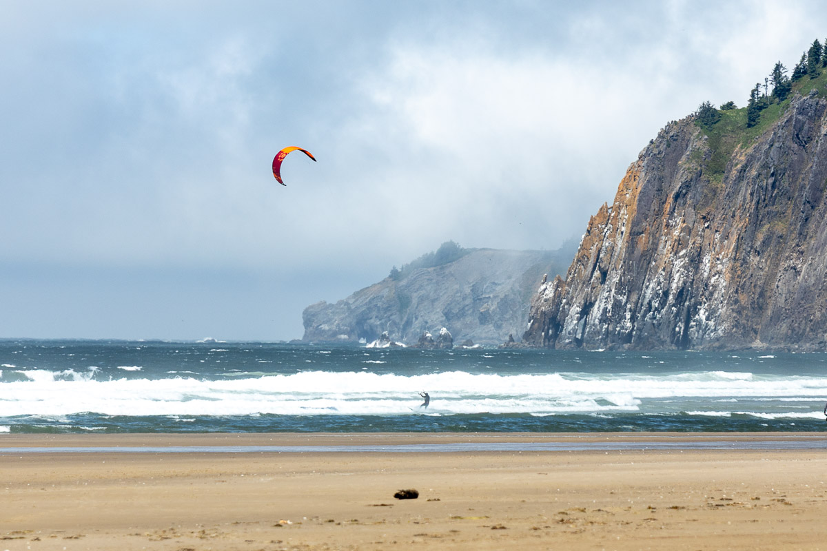 Paraglider with cliffs in back at Manzanita Beach.