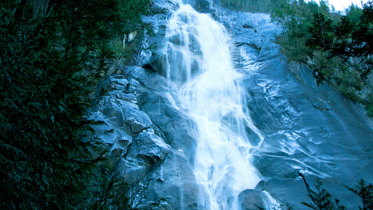 a very tall waterfall in the middle of a forest