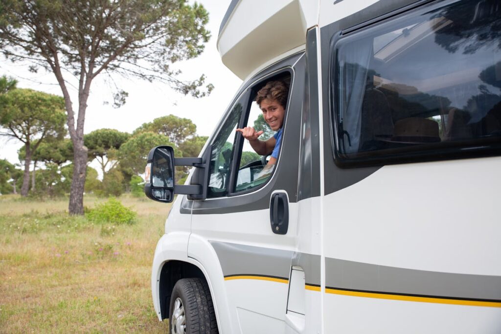 Smiling man driving a camper van through scenic countryside in Portugal, enjoying the adventure.