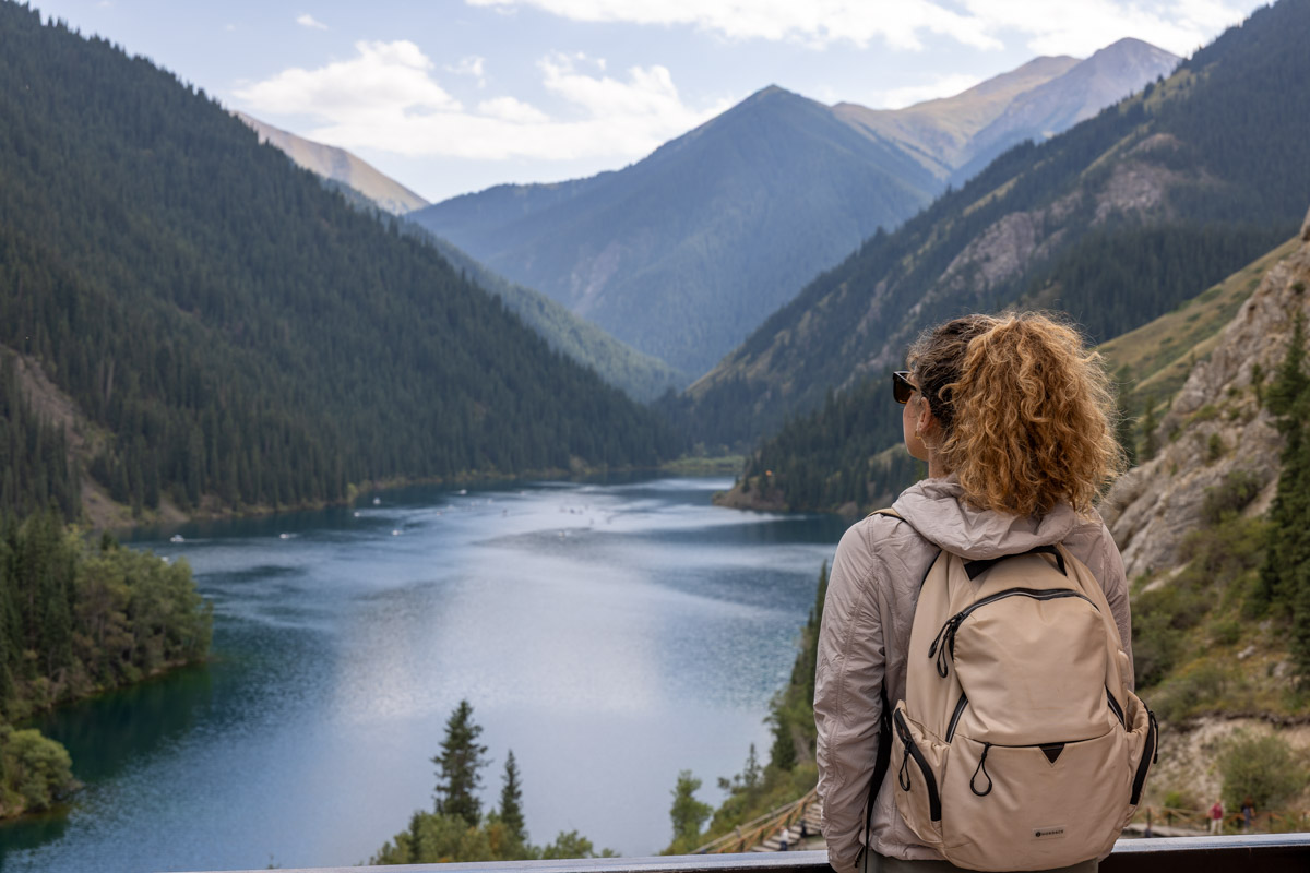 Nina at lake wearing white backpack and Kuhl jacket.
